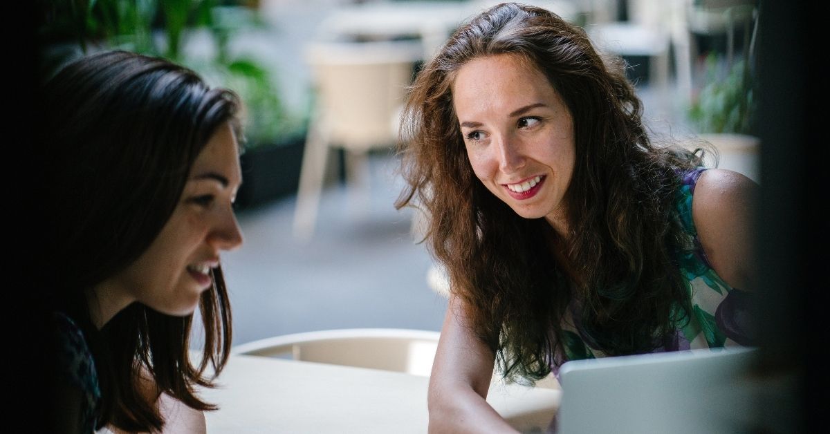 two women talking and smiling discussing advantages of a finance broker